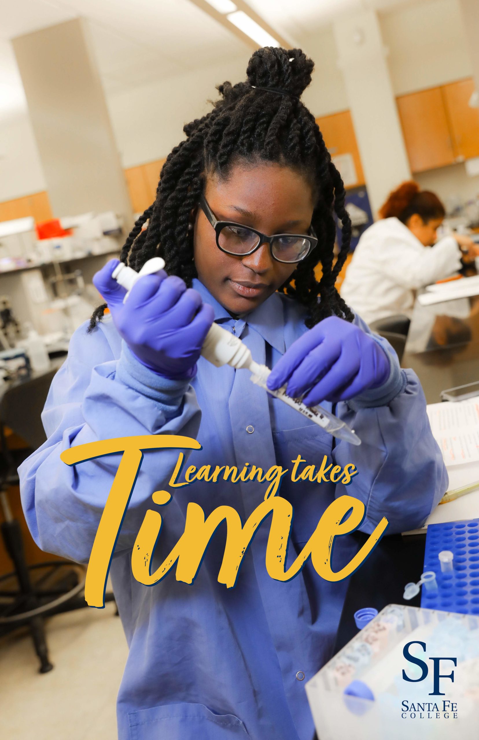 A young woman with black braids, dark hair, thick glasses and purple scrubs is gloved up and working in a chemistry lab.