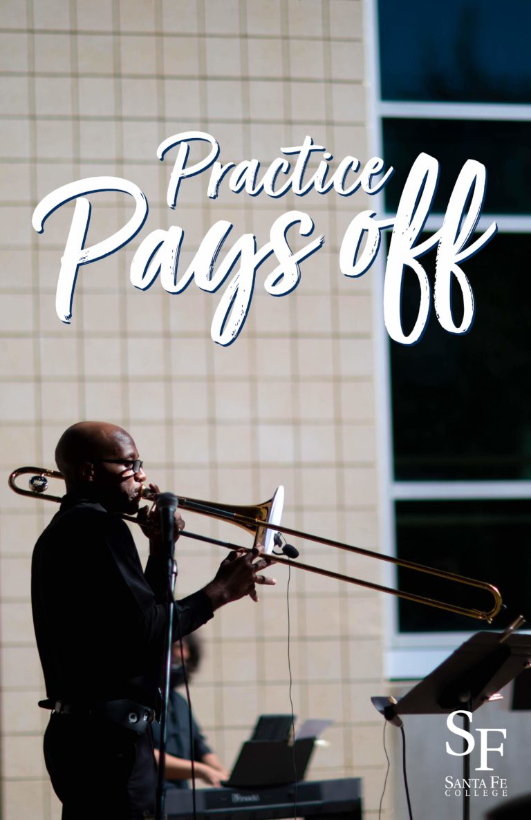 A black man in black dress clothes, iPhone clipped to his belt, is outside on a sunny day, blowing into a shiny trombone. He's got microphones on him and a keyboardist is playing in the background.